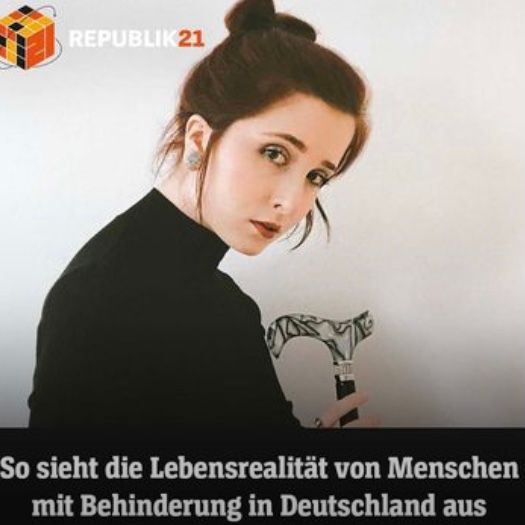 Luisa trägt einen schwarzen Rollkragenpulli und ihre roten Haare in einem hohen Dutt. Vor sich hält sie ihren schwarz/weißen Gehstock mit Strass. Sie schaut ernst in die Kamera. Darüber ist das Logo von Republik 21, ein orangener Würfel. Darunter steht: So sieht die Lebensrealität von Menschen mit Behinderung in Deutschland aus